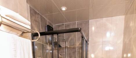 Een moderne badkamer met een douche met glazen wand, een toilet en een handdoekhouder.