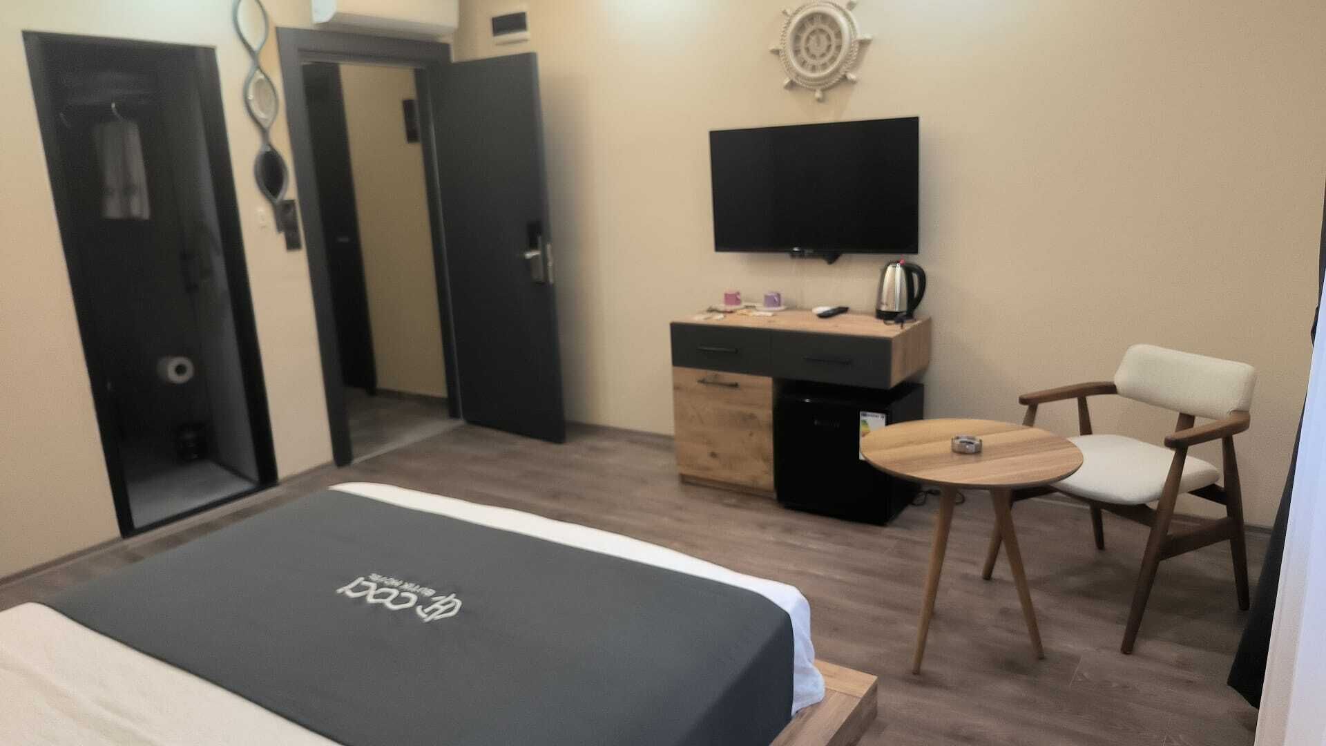 A hotel room with a bed, a desk, a chair, a television, and a small table.