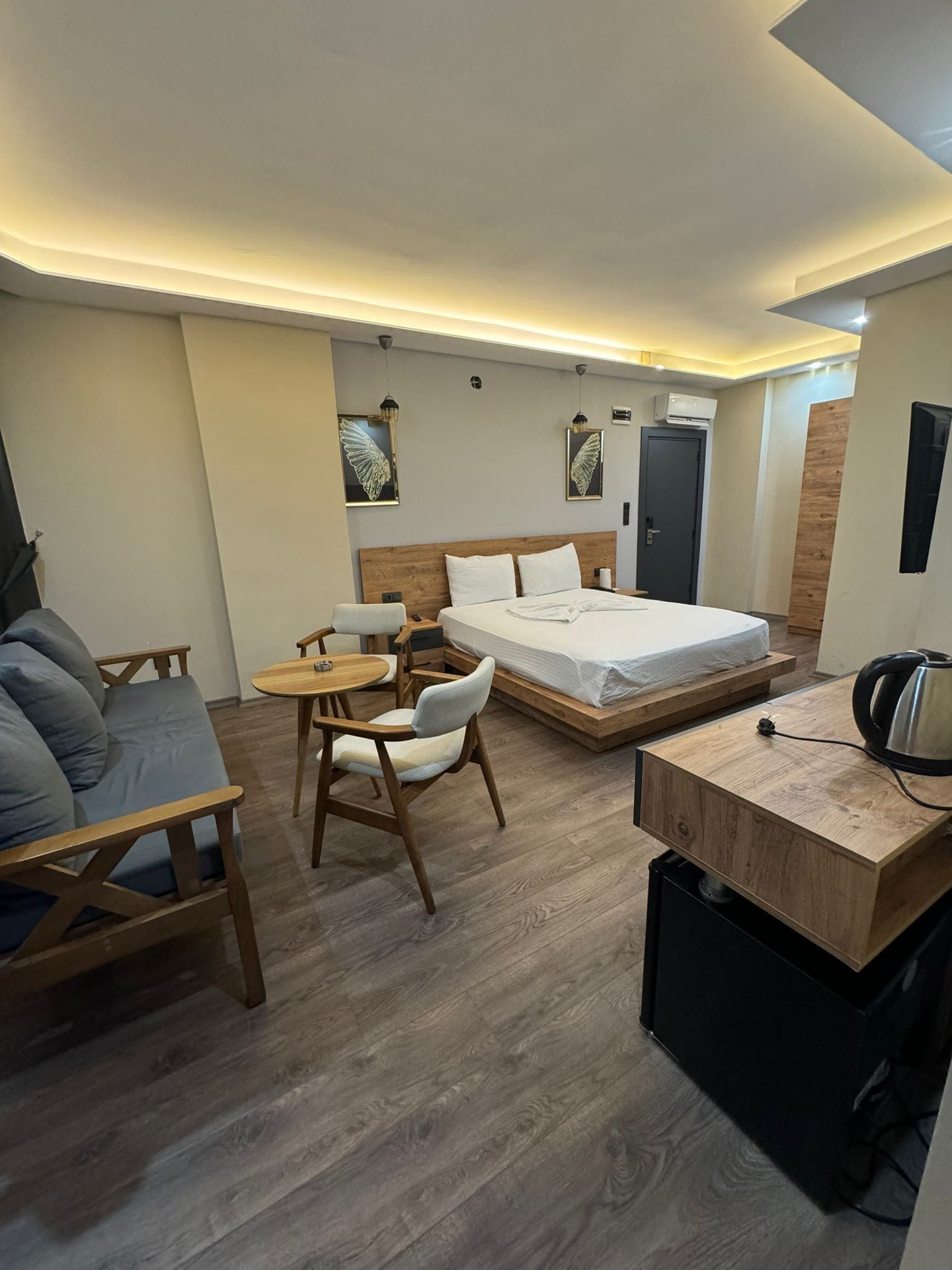 A modern hotel room with a bed, a desk, a chair, and a small table.