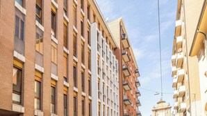A multi-story building with a brick facade, large windows, and balconies. - Lame Pro (Bologna)