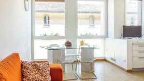A modern apartment with a glass dining table, two chairs, a sofa, and a TV. - Lame Pro (Bologna)