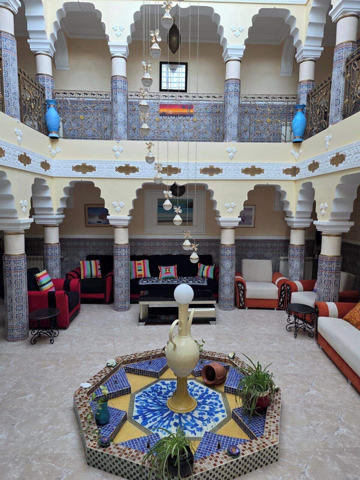 Un intérieur à plusieurs niveaux, doté d’une fontaine centrale, d’espaces aménagés pour s’asseoir et de colonnes décoratives.