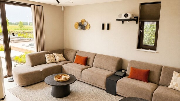 A modern living room with a sectional sofa, two round coffee tables, and a projector on the wall.