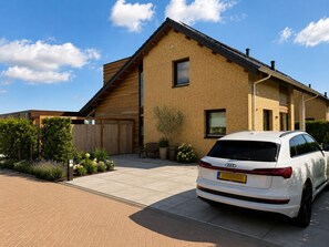 A modern two-story house with a car parked in the driveway.