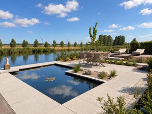 A swimming pool with a deck, lounge chairs, and a table. - Waterfront villa with a jacuzzi and sauna (Leimuiden)