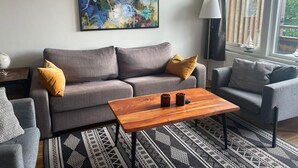A modern living room with a grey sofa, a wooden coffee table, patterned rug, and a large abstract painting on the wall. - 5 Star Holiday Home in Uddevalla (Uddevalla)