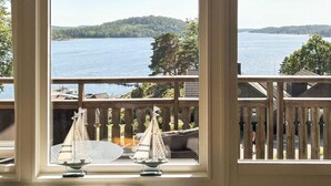 A view from a room with a large window overlooking a lake, with a deck and outdoor furniture visible. - 5 Star Holiday Home in Uddevalla (Uddevalla)