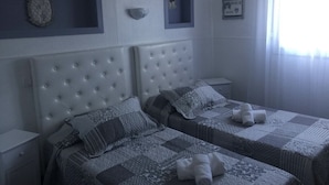 Quarto com duas camas, cabeceiras, mesas de cabeceira e uma janela com cortinas.