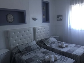 A bedroom with two beds, a headboard, bedside tables, and a window with curtains. - luberon hotel restaurant family (Apt)