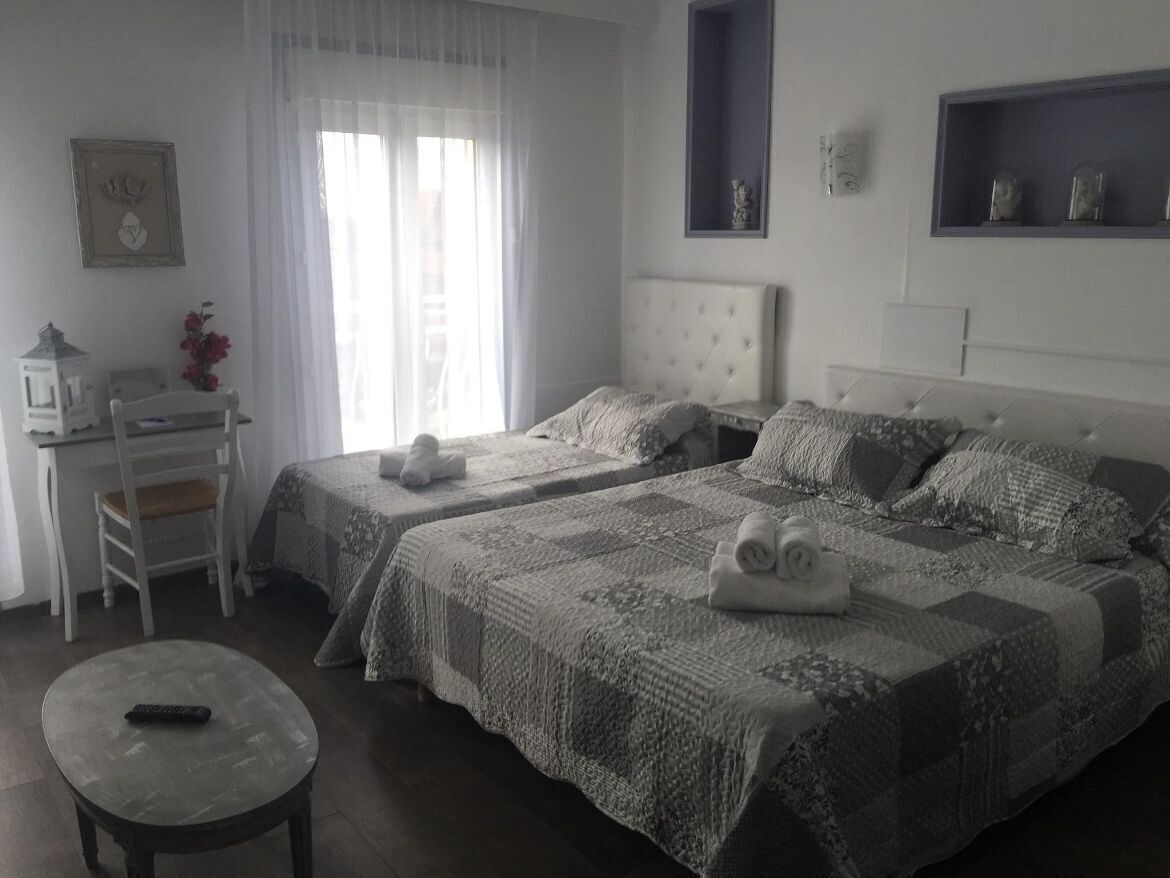 Ein Schlafzimmer mit zwei Betten, einem Schreibtisch, einem Stuhl und einem kleinen Tisch.