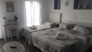 Um quarto com duas camas, uma escrivaninha, uma cadeira e uma mesinha.