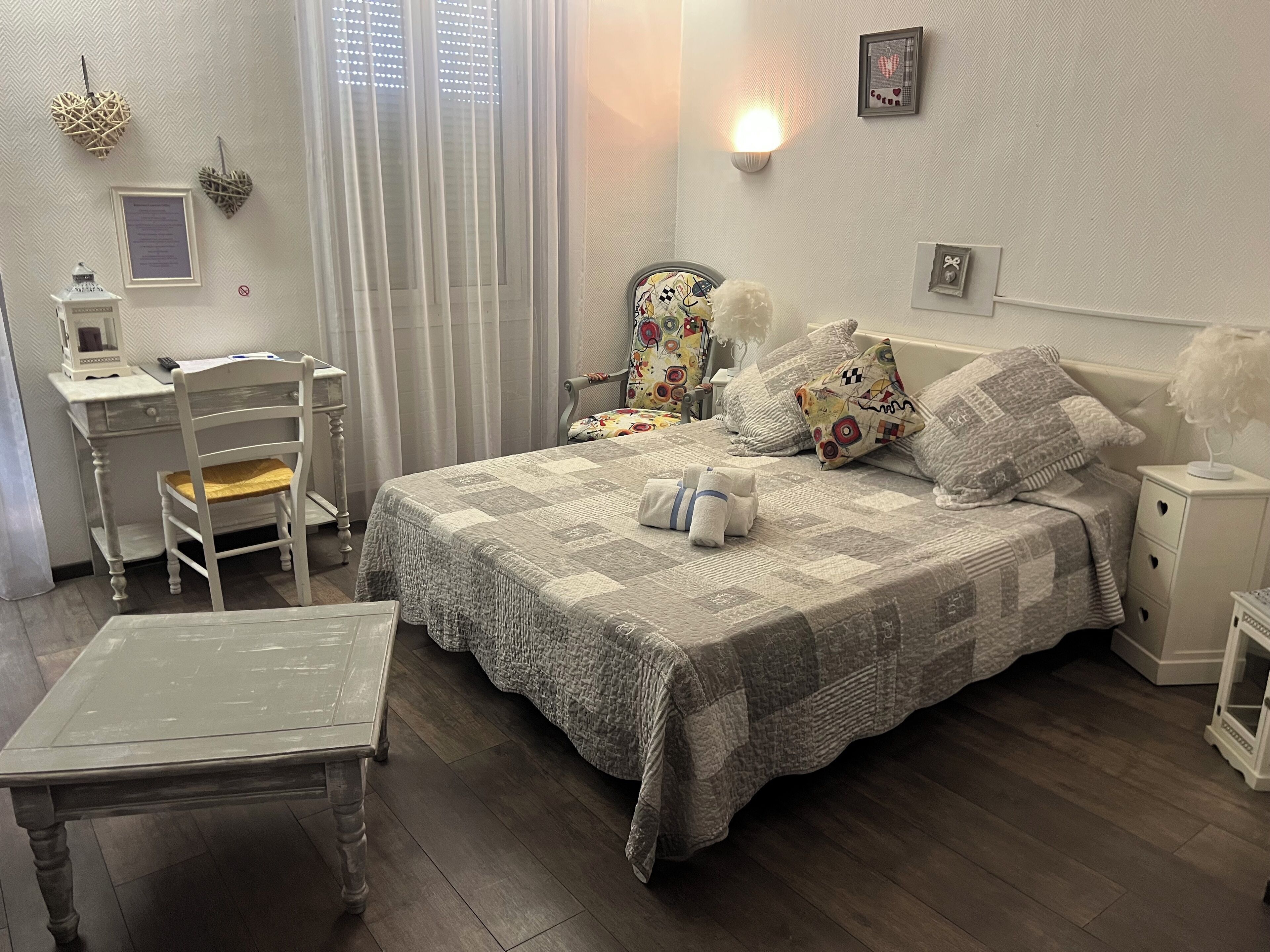 Ein ordentlich eingerichtetes Schlafzimmer mit einem Bett, Nachttischen, einem Schreibtisch und einem Stuhl.