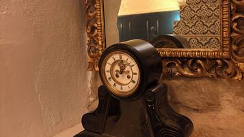 Une horloge murale au design classique, un miroir décoratif doté d’un cadre orné et un mur à motifs en arrière-plan.