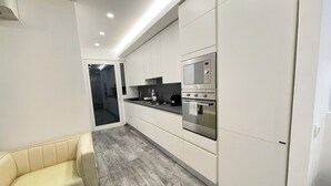 Eine moderne Küche mit weißen Schränken, einem eingebauten Ofen und einem grauen Holzboden.