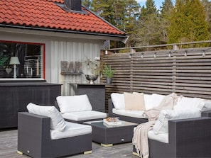 An outdoor seating area with wicker furniture and a bar sign. - 5 Star Holiday Home in Svanesund (Svanesund)