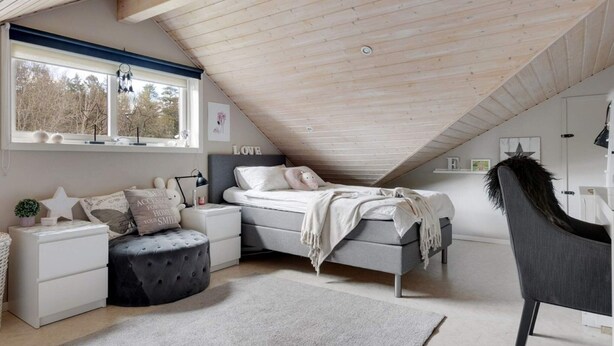 A bedroom with a sloped ceiling, a bed, a nightstand, a chair, and a window with star decorations. - 5 Star Holiday Home in Svanesund (Svanesund)