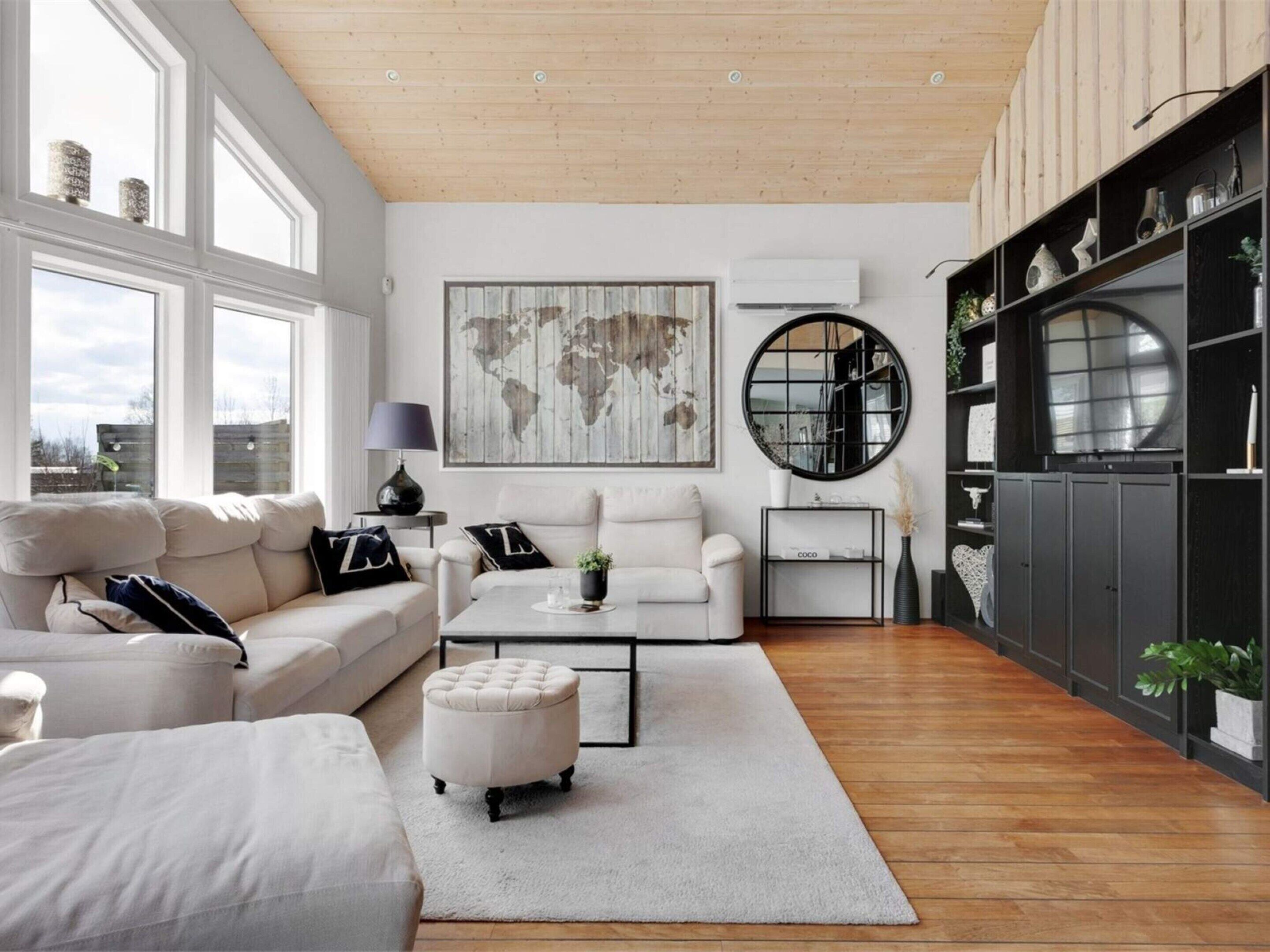 Un salon moderne comprenant un canapé, un pouf, une table basse et une œuvre d’art représentant une carte du monde.