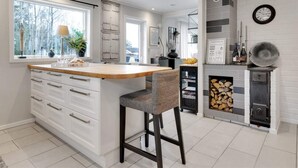 A modern kitchen with a central island, white cabinetry, and a fireplace. - 5 Star Holiday Home in Svanesund (Svanesund)