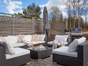 An outdoor patio area with wicker furniture, a grill, and a wooden fence. - 5 Star Holiday Home in Svanesund (Svanesund)