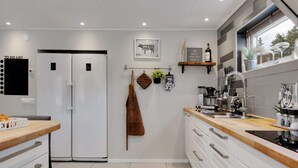 A modern kitchen with white cabinets, a double-door refrigerator, a wooden countertop, and a window with a view. - 5 Star Holiday Home in Svanesund (Svanesund)