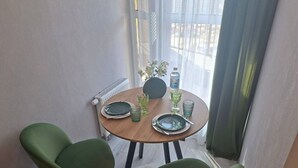 Un comedor con una mesa redonda, dos sillas y un florero con flores.