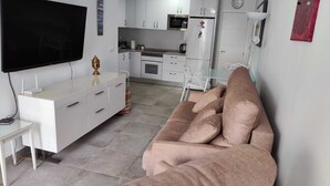 Un salon moderne avec un canapé, un téléviseur et une petite table.