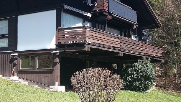 Un immeuble de deux étages doté d’un balcon, de grandes fenêtres et d’une antenne parabolique.