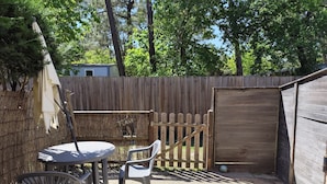 Un patio con una mesa, sillas, una cerca de madera y un cobertizo.
