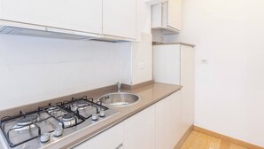 A kitchen with a gas stove, sink, and white cabinets.