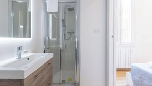 A modern bathroom with a glass shower enclosure, a white sink, and a wooden vanity.