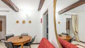 Een eethoek met een ronde tafel, stoelen en een rode sofa met een patroon.