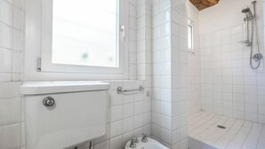 Een badkamer met toilet, hygiëneschuimer en douche.