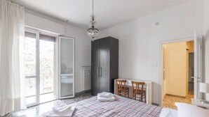 Ein Schlafzimmer mit Bett, Schreibtisch, Stuhl, Kleiderschrank und einer Tür zu einem anderen Raum.
