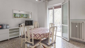 Ein Zimmer mit Esstisch, Stühlen, Fernseher, Heizkörper und einem Fenster mit Blick.