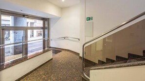 Een modern interieur met een glazen balustrade, een trap en uitzicht op de straat.
