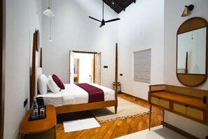 Ein Schlafzimmer mit Bett, Nachttisch, Spiegel und einer Tür zu einem anderen Raum.