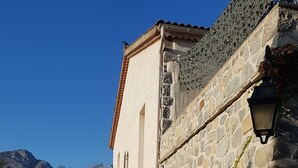 A stone building with a tiled roof, a large potted plant, and a pathway leading to an arched entrance. - GRAPI Farm with a swim spa for 4 adults and 4 children (CALVI)