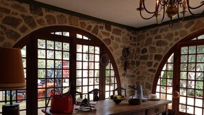 A rustic room with stone walls, wooden furniture, and large windows. - GRAPI Farm with a swim spa for 4 adults and 4 children (CALVI)