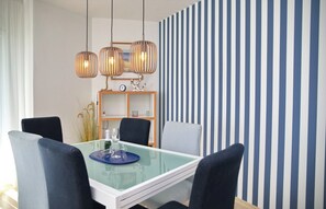 A dining area with a glass table, four chairs, and a striped wall in the background. - Tannenburg Apartment 107 - A Beachfront Vacation with Room for the Whole Family (Grömitz)