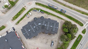 An aerial view of a parking lot with multiple cars and a large building with a grey roof.