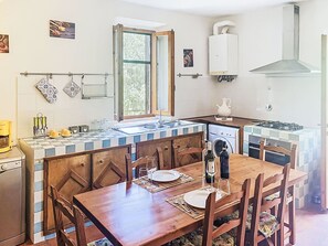 A compact kitchen with a dining area, a window, a washing machine, and a gas stove. - La Camporena by Interhome (Greve in Chianti)