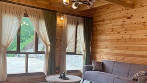 A wooden interior with a sofa, a round table, and a chandelier. - Derya Dağ Evi (Çamlıhemşin)