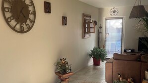 A dining area with wicker furniture, a large wall clock, and a potted plant. - A haven of peace (Néoules)