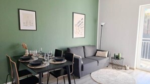 En matplats med ett bord dukat för fyra personer, en grå soffa och ett litet sidobord med en lampa.