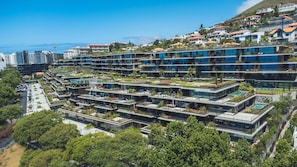Ein modernes Mehrstöckiges Hotel mit Dachgärten und Blick auf das Meer.