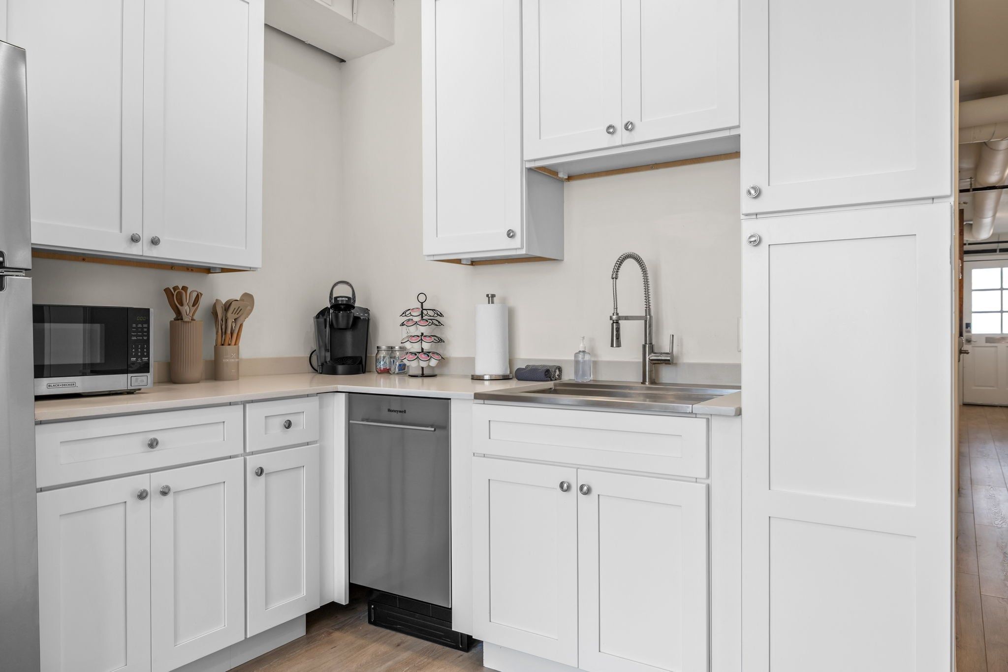 A modern kitchen with white cabinetry, a stainless steel sink, and a microwave.