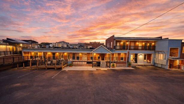 Un hotel con patio central, varias construcciones y cielo al atardecer.