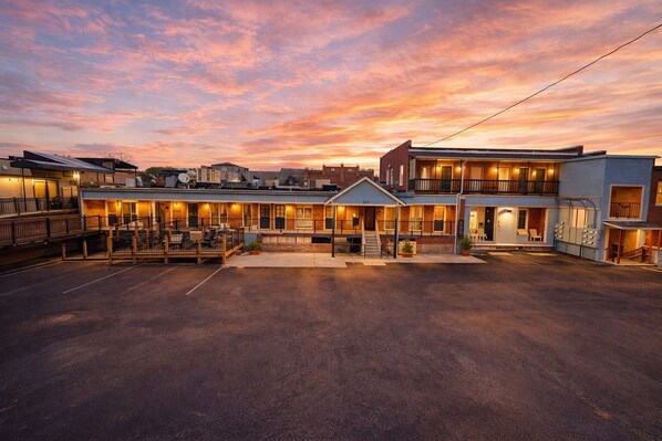A hotel with a central courtyard, multiple buildings, and a sunset sky.