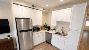 Una cocina moderna con armarios blancos, electrodomésticos de acero inoxidable, microondas y lavavajillas.