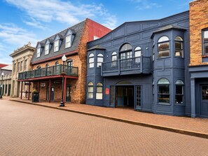 A row of brick buildings with a mix of architectural styles, including a building with a balcony and another with a large arched window.
